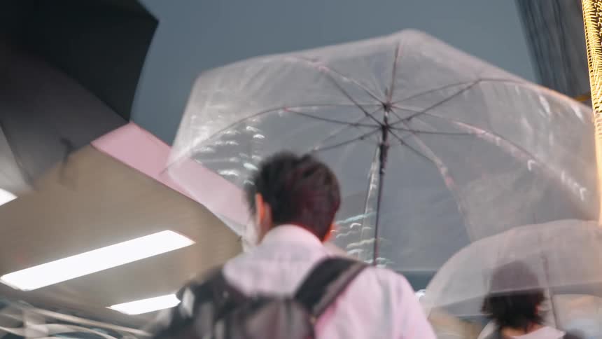 Crowd of people walking along the sidewalks of a metropolis at night using umbrellas