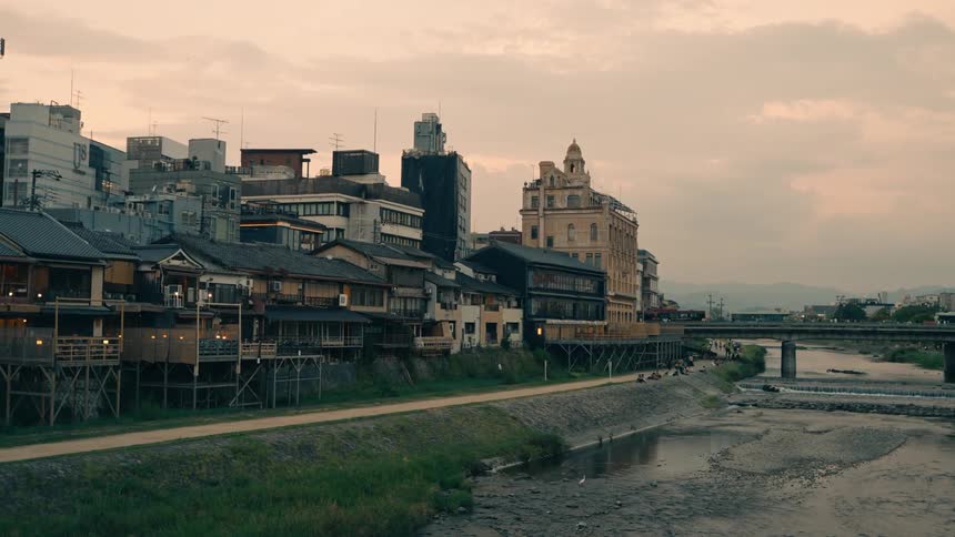 A cityscape beside a dry river with diverse buildings and a bridge