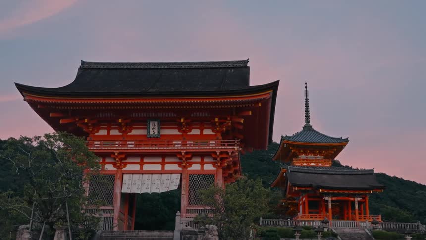 Two pagoda style structures surrounded by a forest and mountains