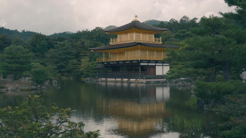 A yellow pagoda sits next to a lake