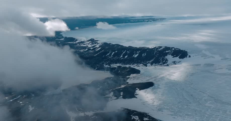Aerial panorama of a day with lots of clouds overlooking mountains covered in snow