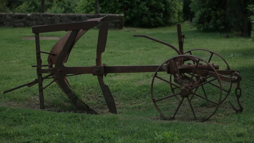 A rusty piece of old farm equipment sitting in a yard
