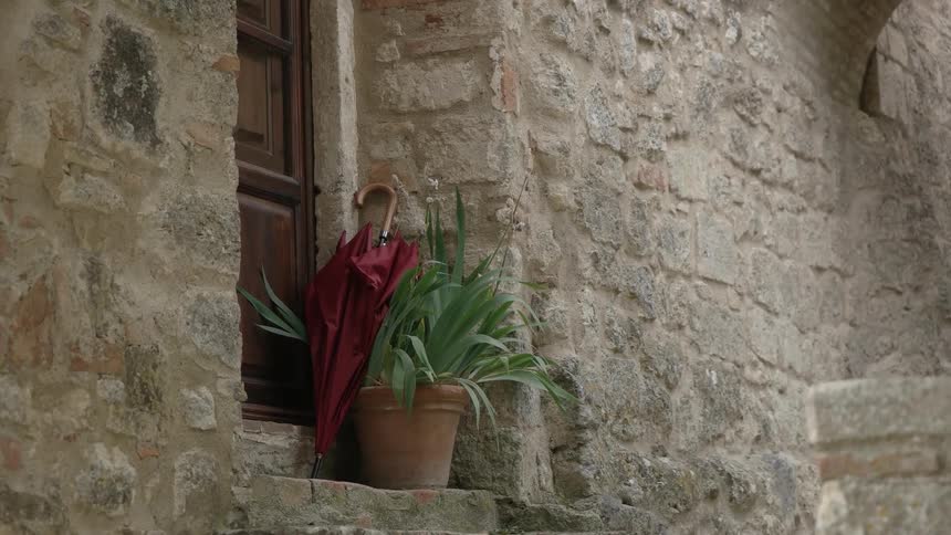 An umbrella rests against a stone wall in front of a door