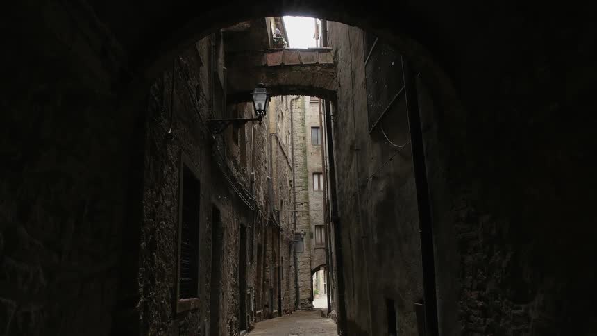The alley is dark with tall buildings on either side
