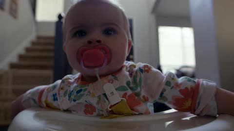 Closeup of a babys face sucking a pacifier in a walker