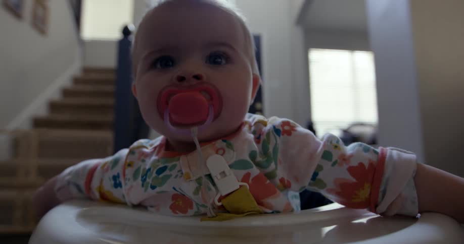 Closeup of a babys face sucking a pacifier in a walker