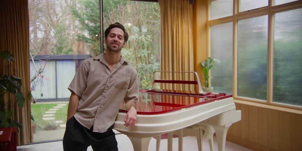 A man is leaning against his piano