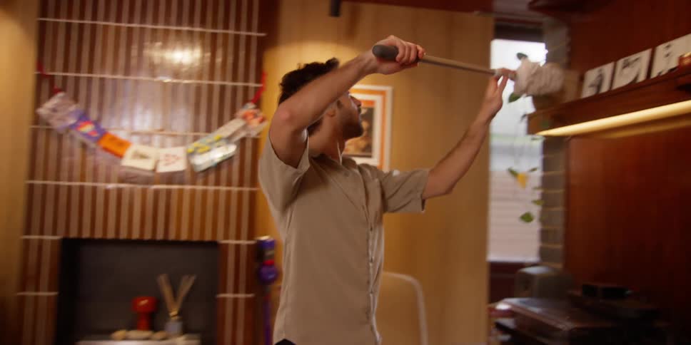 Man playfully dusts christmas decorations in wood paneled room