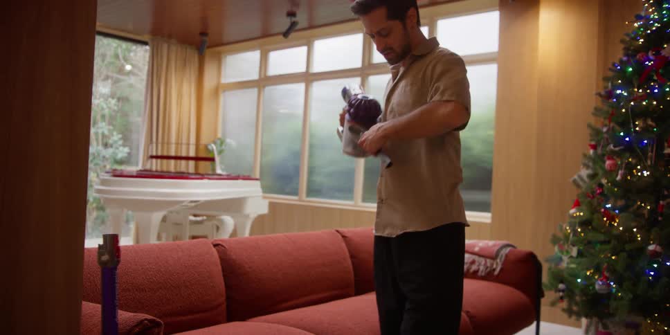 A man cleaning the sofa in the living room
