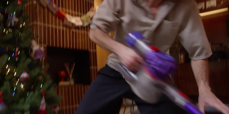 Man dancing and vacuuming a carpet in the living room