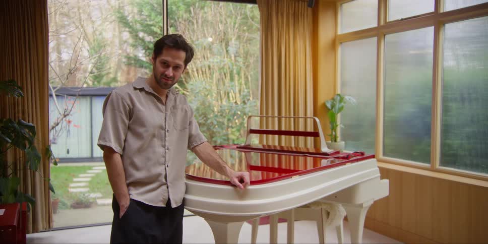 A man is leaning against his piano