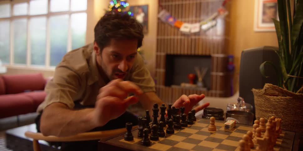 Portrait of a man dancing in the room and at the same time arranging the pieces on a chessboard
