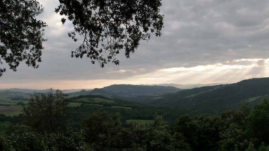 Sunlight shines through clouds in a hilly and rural area