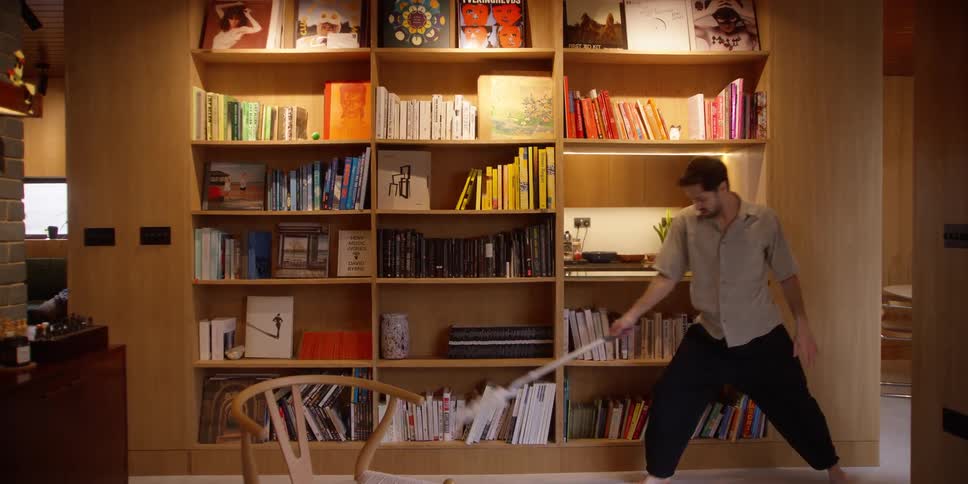 A man doing the dance move while cleaning a bookshelf