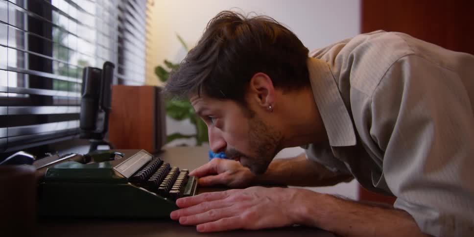 A man leans forward typing on his keyboard