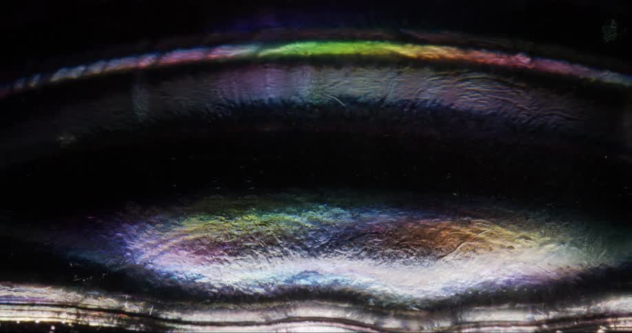 Light reflecting off the liquid is making rainbow colors