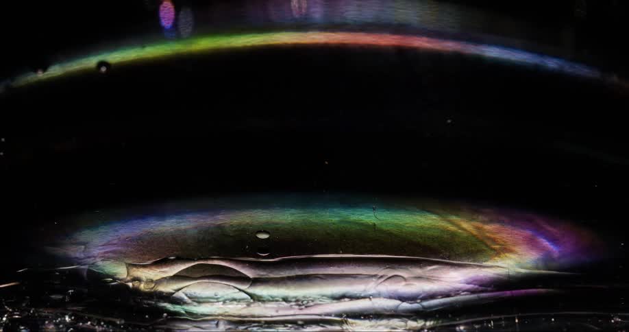 A dim light refracts off of the surface of a viscous fluid in the dark