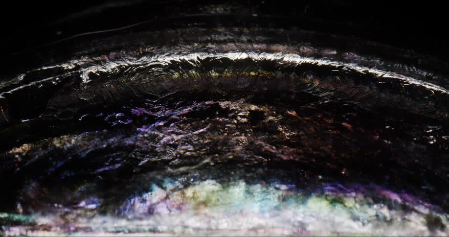 A liquid moving on a black surface with several points of lights on the surface of the liquid
