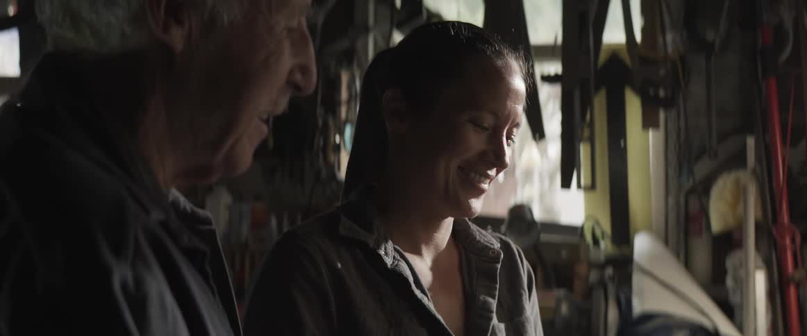 An old man is showing a woman how to put out a blowtorch that is breathing fire
