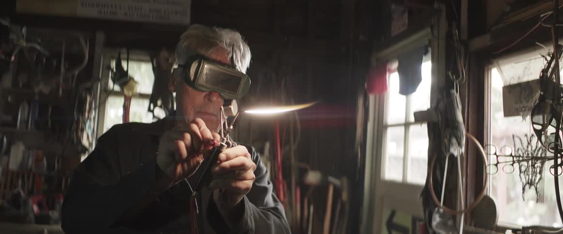 Man standing in workshop lights blowtorch with a striker then adjusts the flame