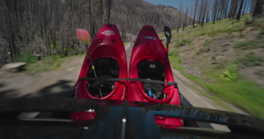 A back view of a moving truck transporting two red canoes