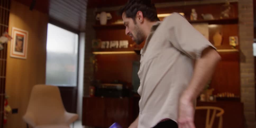 Man dances barefoot while vacuuming floor near christmas tree
