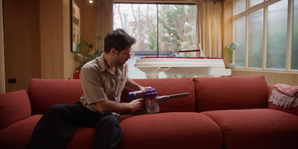 A man vacuums his couch