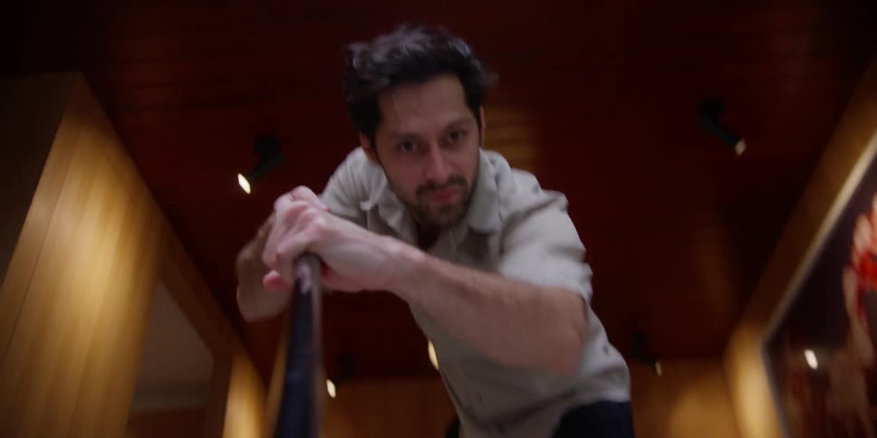 A man picks up an object and then passes it back and forth across the floor