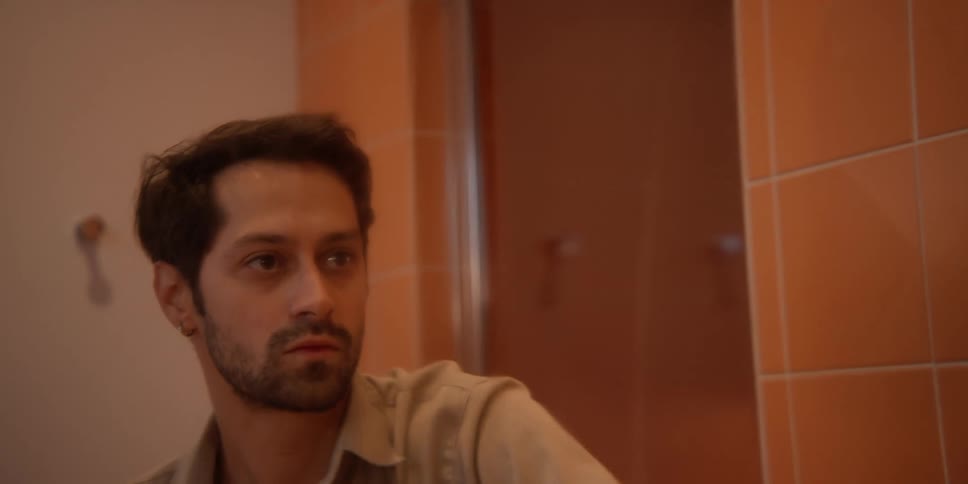 A man sprays cleaner on a mirror and wipes it off
