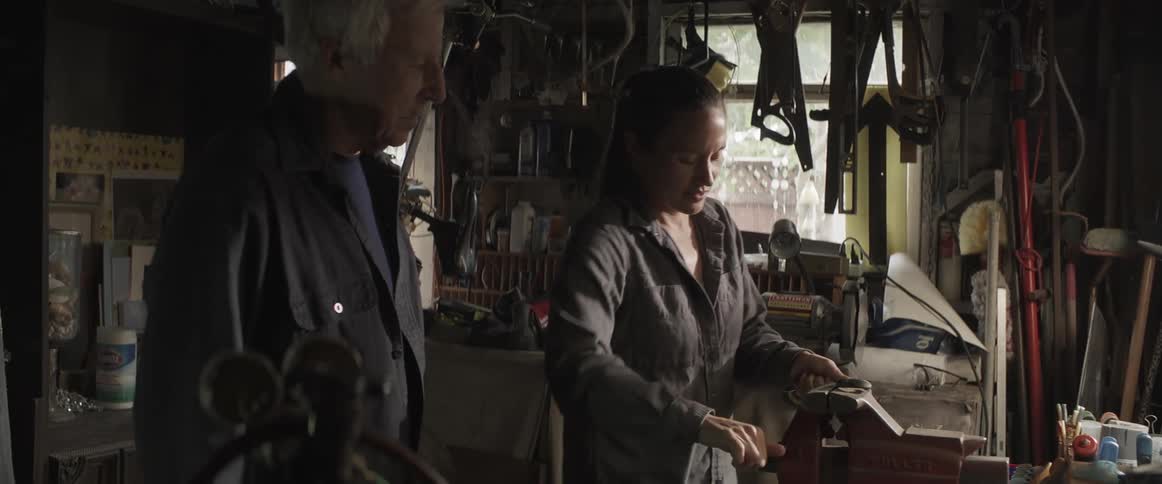 A woman trying hard to bend an object in a vice while a man is next to her and then they both do high five