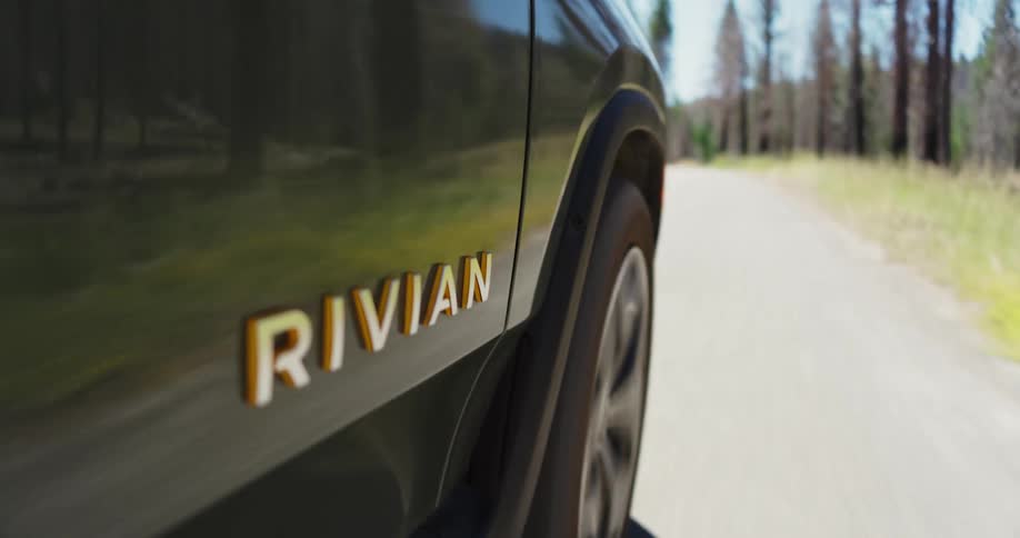The outside of a black car that is driving on a street with several trees on the sides