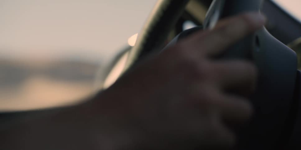 Closeup of a mans hand under the steering wheel of a vehicle