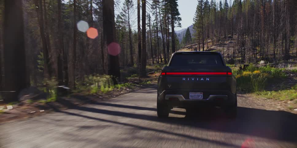 Black truck running quickly down a simple street in the middle of a forest