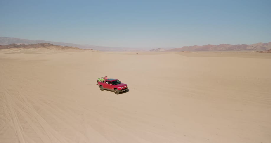 Aerial of a pickup truck driving through the desert during a hot day