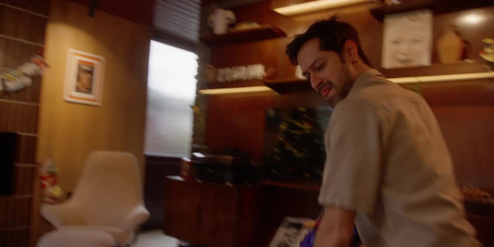 A man dances while cleaning a living room with a cordless vacuum