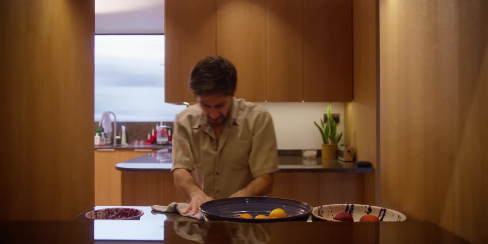 A man cleaning the surface of a table while making artistic dance moves