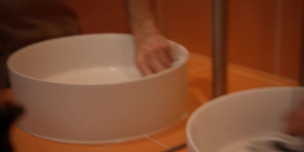 A person using a cloth to clean a white circular sink