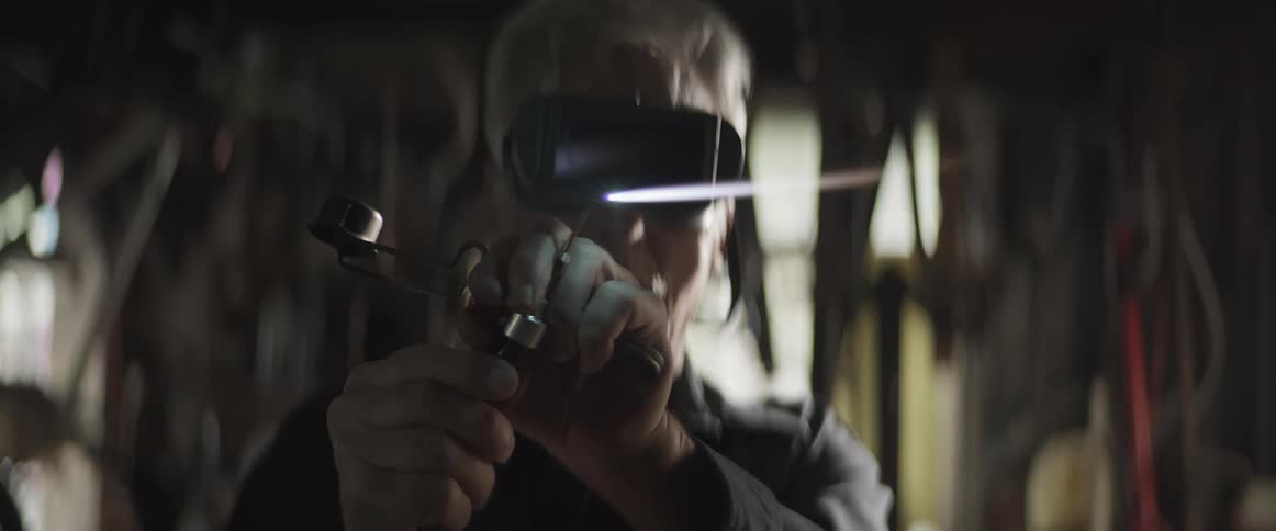 A grayhaired man with glasses is adjusting the power of a blowtorch