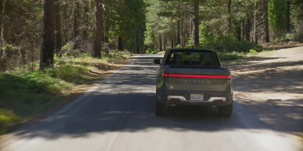 A truck is driving down the road in the woods