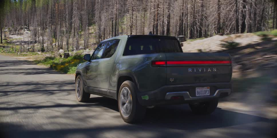 A truck is driving on a road through the woods