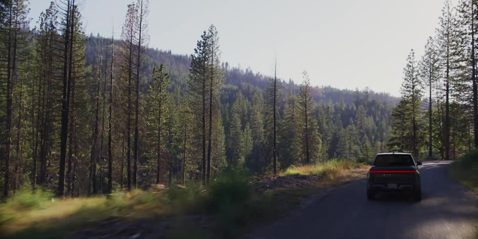 Black pickup truck traveling along a simple street in the middle of a forest during the day
