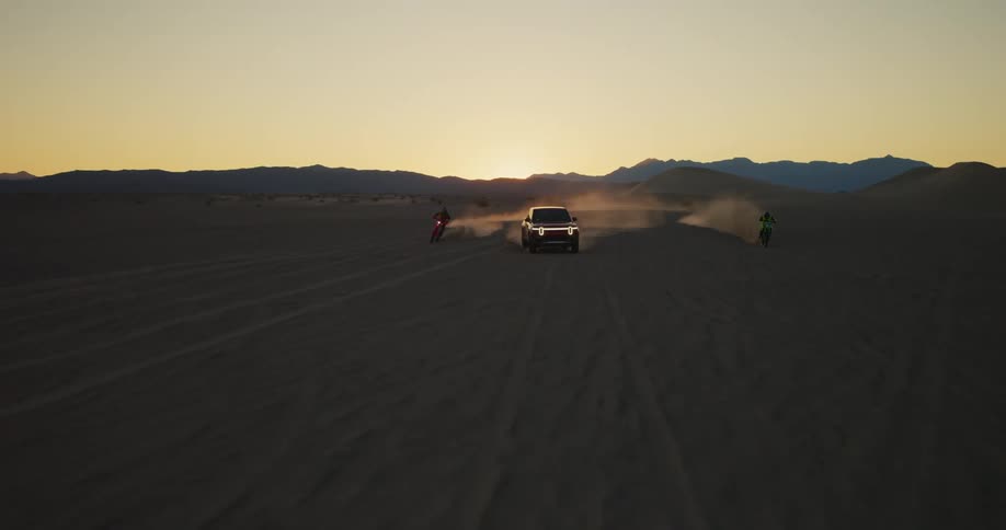 Two motorcycles in a pickup truck running at high speed through the desert and a late afternoon