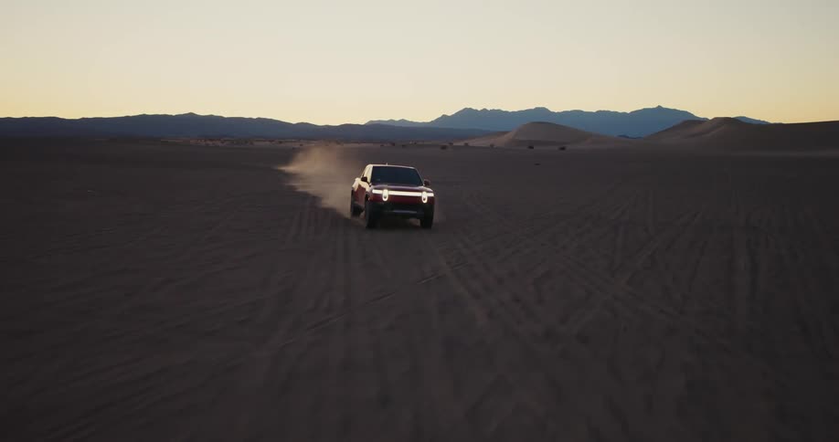 Aerial of a pickup truck driving at high speed through the desert during sunset