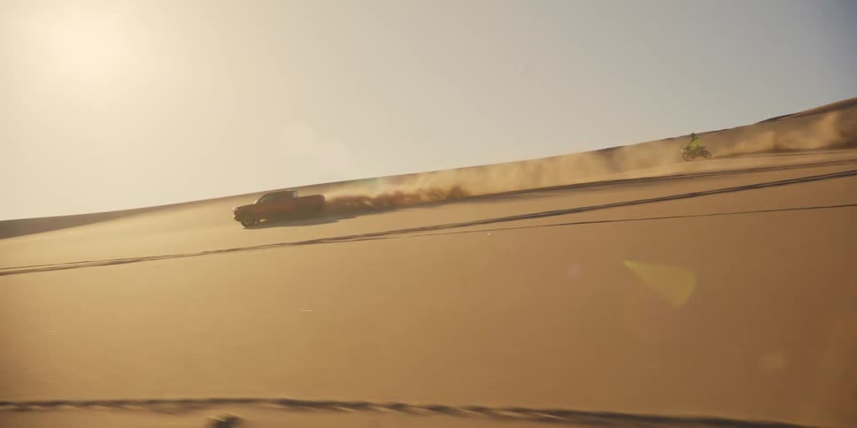 Two motorcycles and a pickup truck racing in the desert