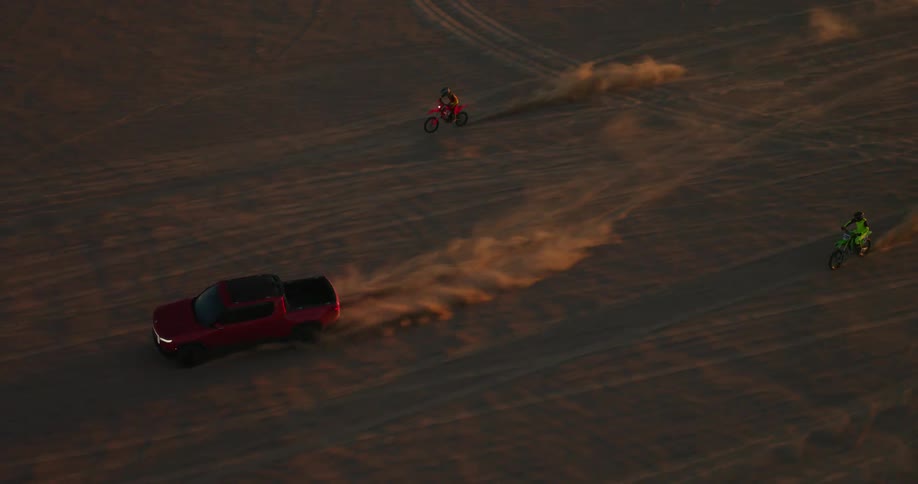 Two motorcycle follow a truck in the desert