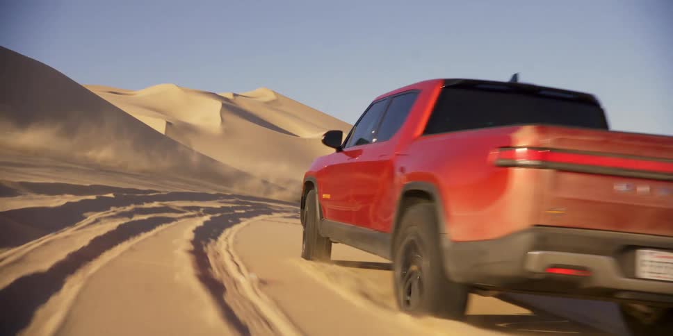 Two motorcycles and a pickup truck racing in the desert