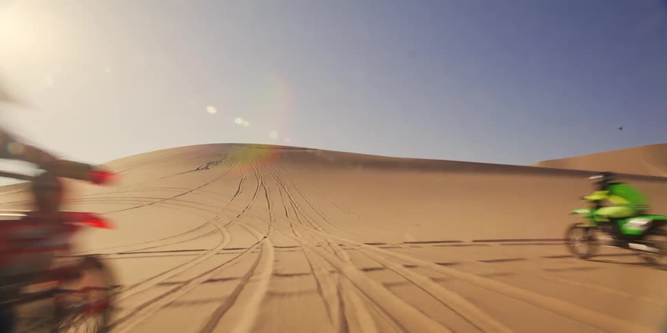 Motorcyclists ride motorcycles at high speed in the desert during the day