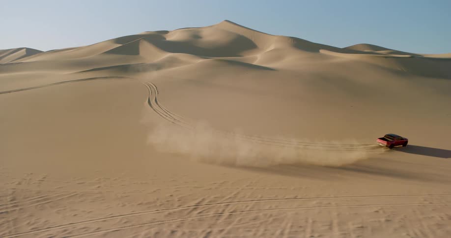 Red truck at high speed making curves through the desert dunes
