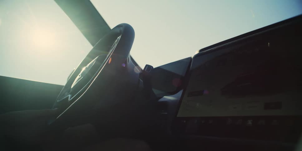 A person with their hand on the steering wheel driving a car