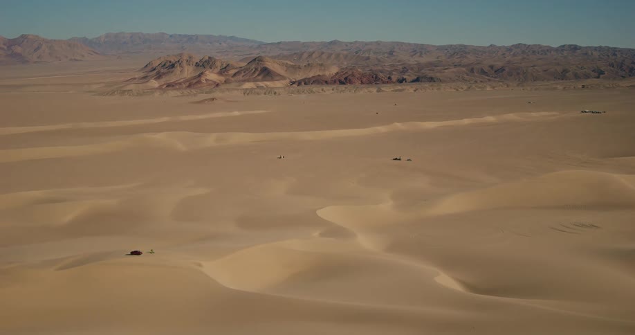 A desert with huge sand dunes and mountains in the background